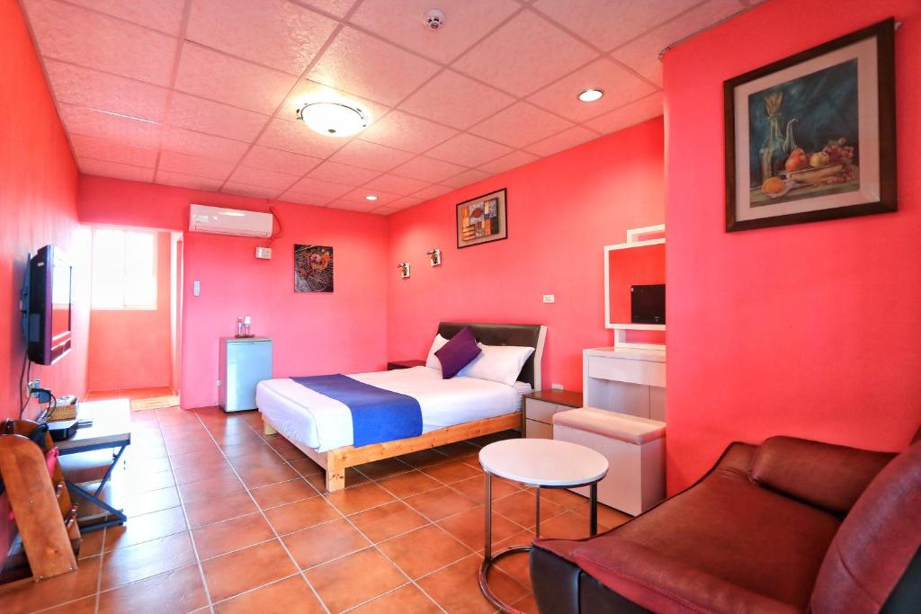 a bedroom with red walls and a bed and a couch at Fumigate Hotel in Hengchun South Gate