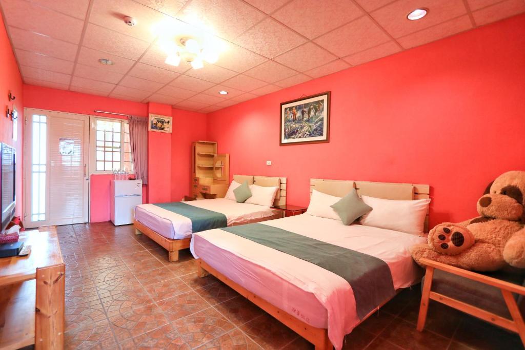 a red bedroom with two beds and a teddy bear at Fumigate Hotel in Hengchun South Gate
