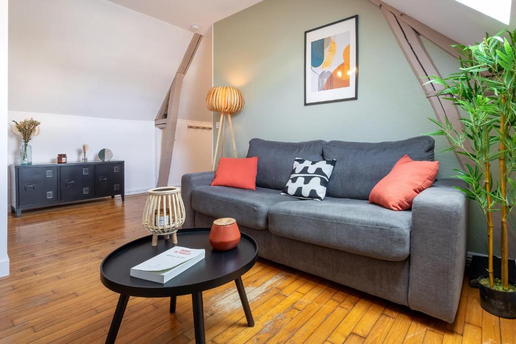 a living room with a couch and a table at Le Cocon Forestier - Proche aéroport Beauvais, Chantilly, forêt de Hez-Froidmont, parking public gratuit, Wifi &amp; Netflix in Clermont