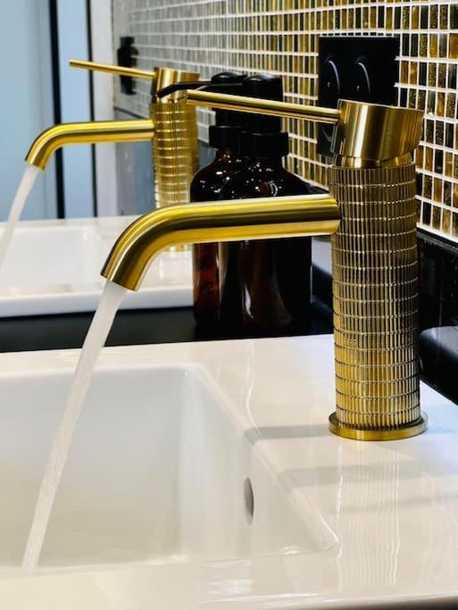 La salle de bains est pourvue d'un lavabo avec un robinet en or. dans l'établissement La Suite Saint Roch, à Villeréal