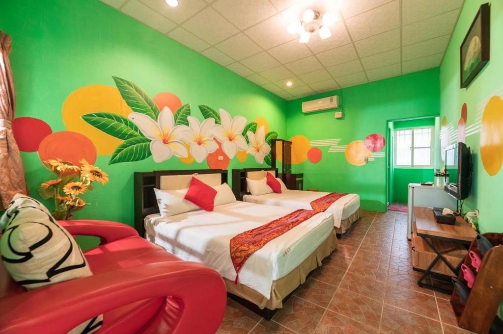 a green bedroom with two beds and a red chair at Fumigate Hotel in Hengchun South Gate