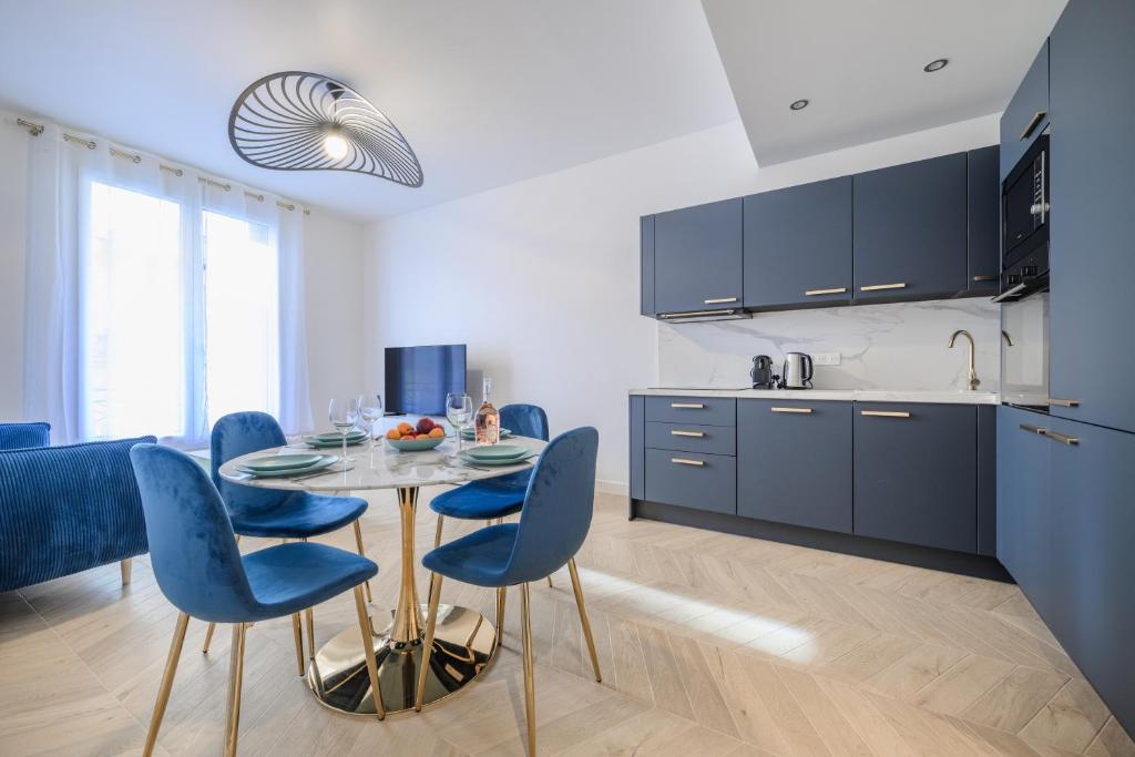 une cuisine et une salle à manger avec une table et des chaises bleues dans l'établissement Le Walesa, magnifique 3P, spacieux et rénové, Port de Nice, à Nice