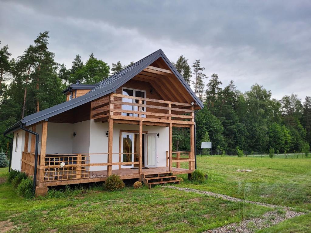 une petite maison avec un toit en gambrel sur un champ dans l'établissement Mazurska Osada Domki, à Rydzewo