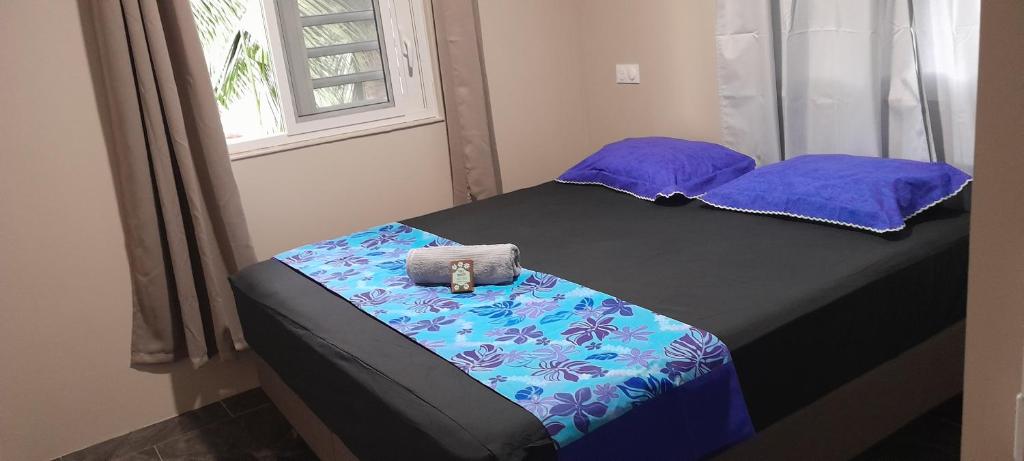 Cama con sábanas y almohadas moradas y azules en Bora Temahana, en Bora Bora