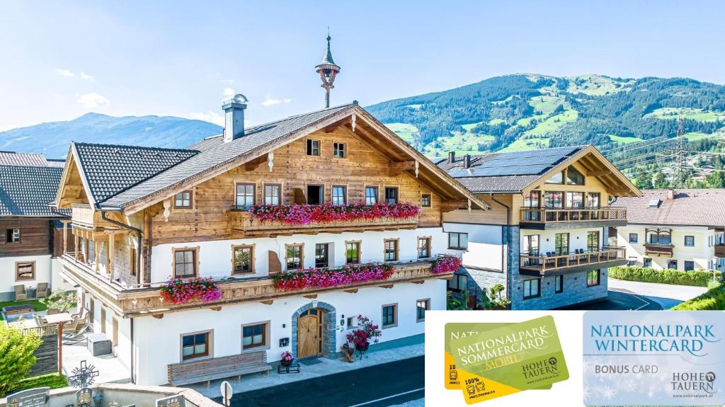 ein großes Holzgebäude mit Blumen davor in der Unterkunft Feriengut Ottacherhof in Hollersbach im Pinzgau