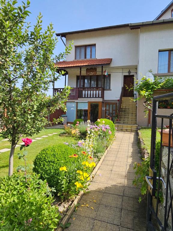 a house with a garden with flowers in front of it at Юндовата къща in Beli Iskar