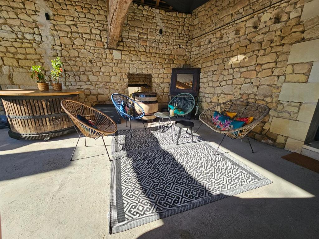 patio z krzesłami, stołem i ceglaną ścianą w obiekcie Le Repaire de Bacchus w mieście Saint-Nicolas-de-Bourgueil