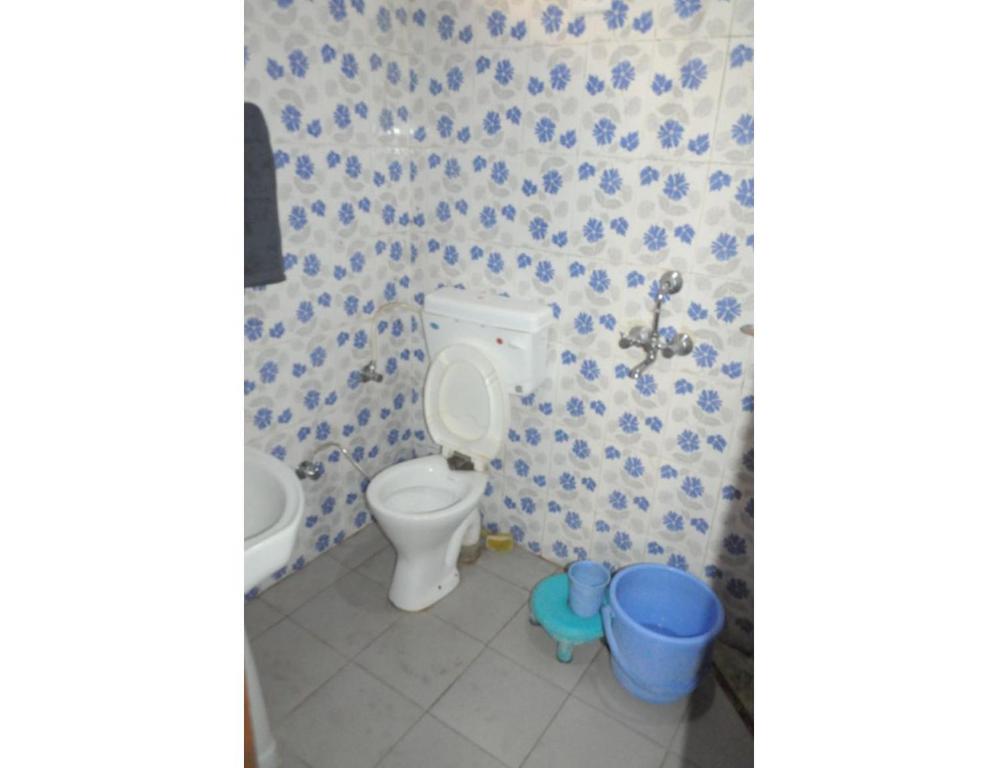 a bathroom with a toilet and two blue buckets at Safaya Paying Guest House and Home Stay, Patnitop in Patnitop