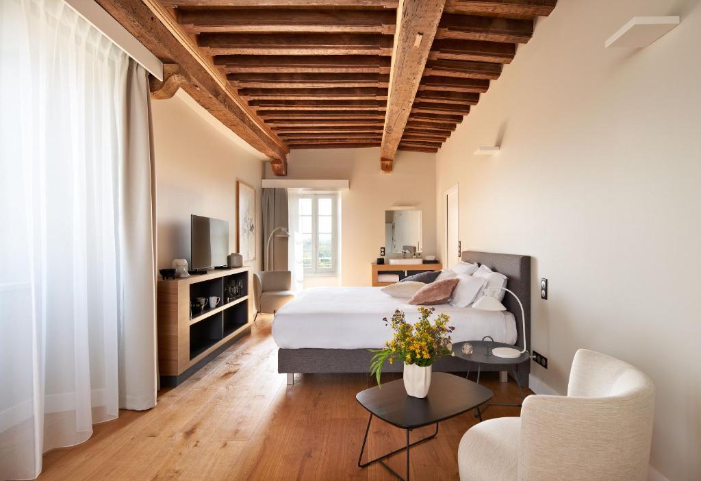 a bedroom with a bed and a couch and a table at hideauts hotels Le Chevalier bleu in Monpazier