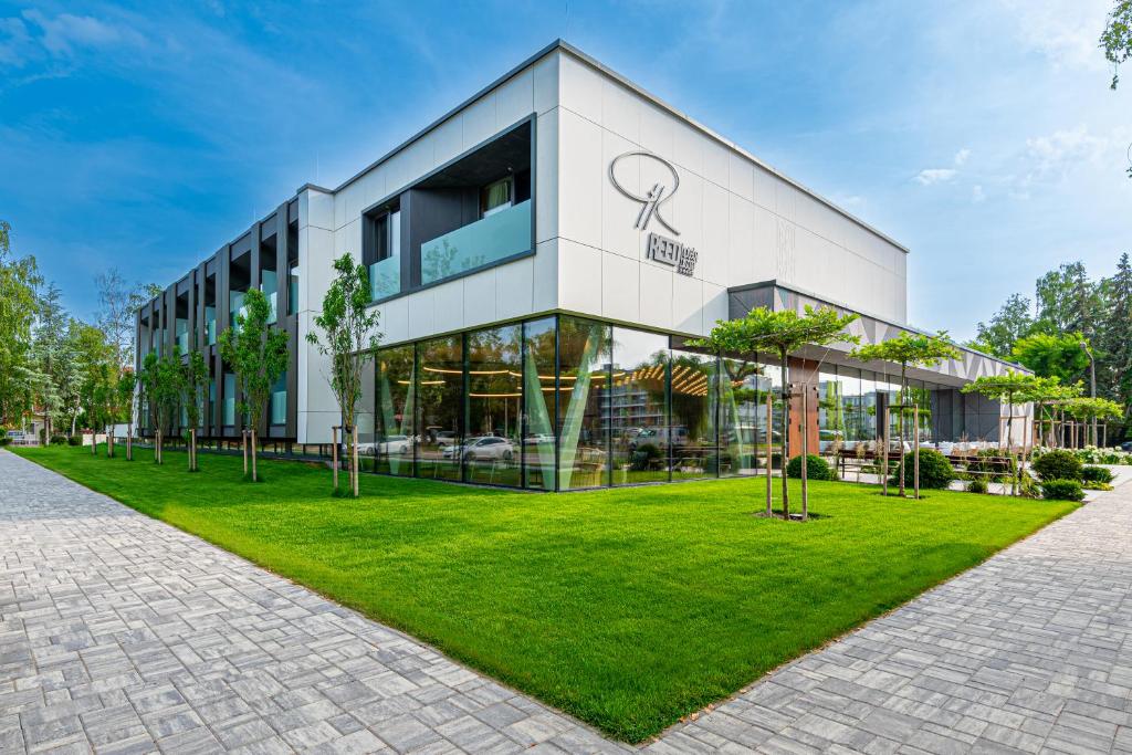 um edifício de escritórios com um relvado verde em frente em REED Luxury Hotel by Balaton em Siófok