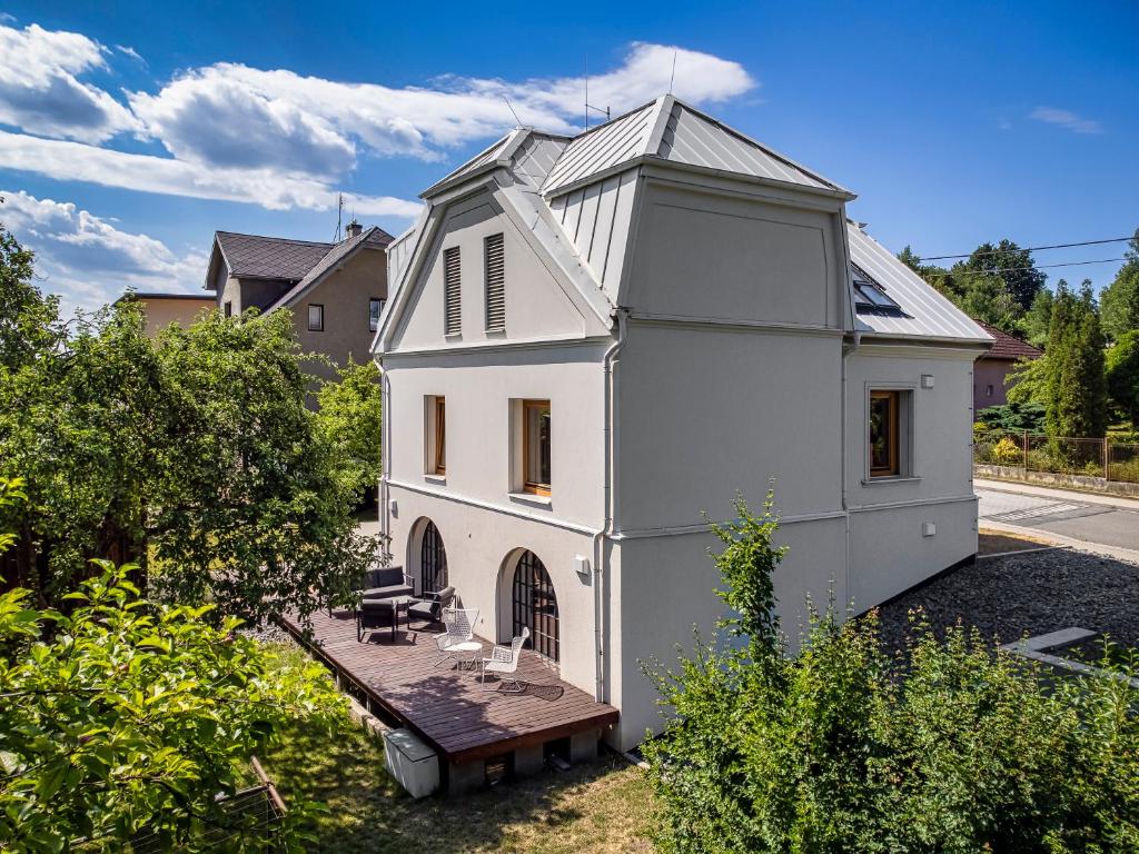 Casa blanca con terraza de madera en el patio en Tiny House, podkrovní apartmán a apartmán s výhledem do zahrady, en Ostrava