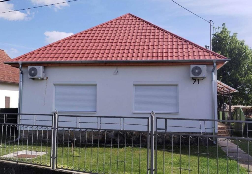 een wit huis met een rood dak bij Valentina apartman in Balatonmáriafürdő