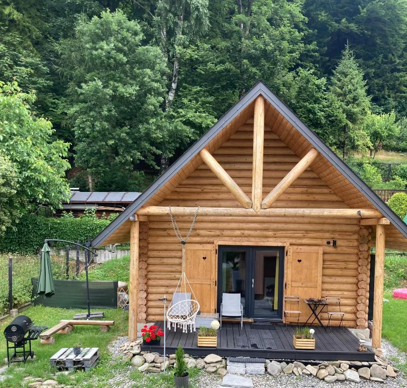 uma cabana de madeira com um alpendre e um baloiço em Chatka pod lasem Bezpłatne Jacuzzi em Szczyrk