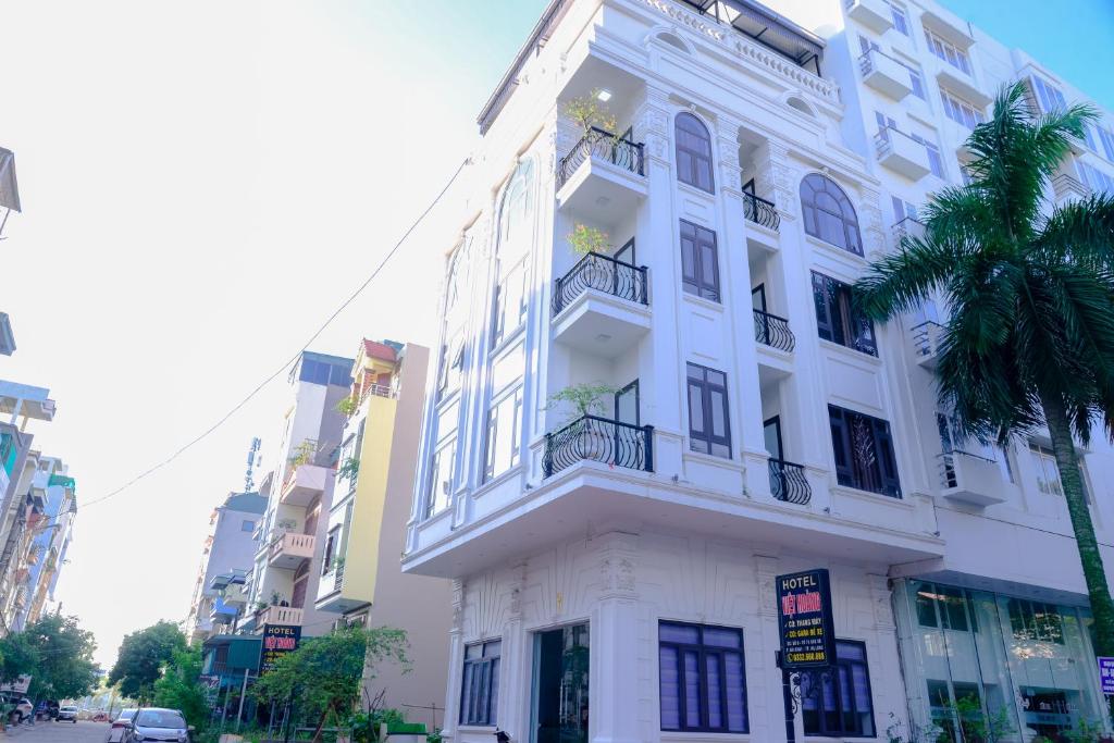 un bâtiment blanc avec un palmier en face dans l'établissement Việt Hoàng Hotel Hạ Long, à Hạ Long