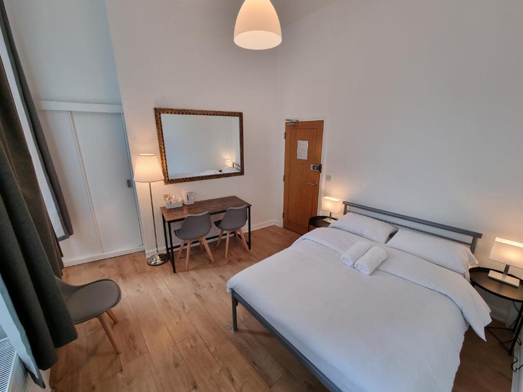 een slaapkamer met een bed, een tafel en een spiegel bij Horangee Pocha in Londen