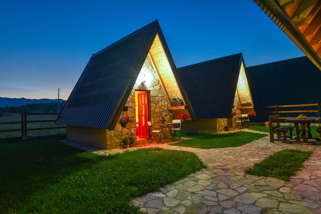 een huis met een rode deur en een tafel bij Cottages Big bear in Žabljak
