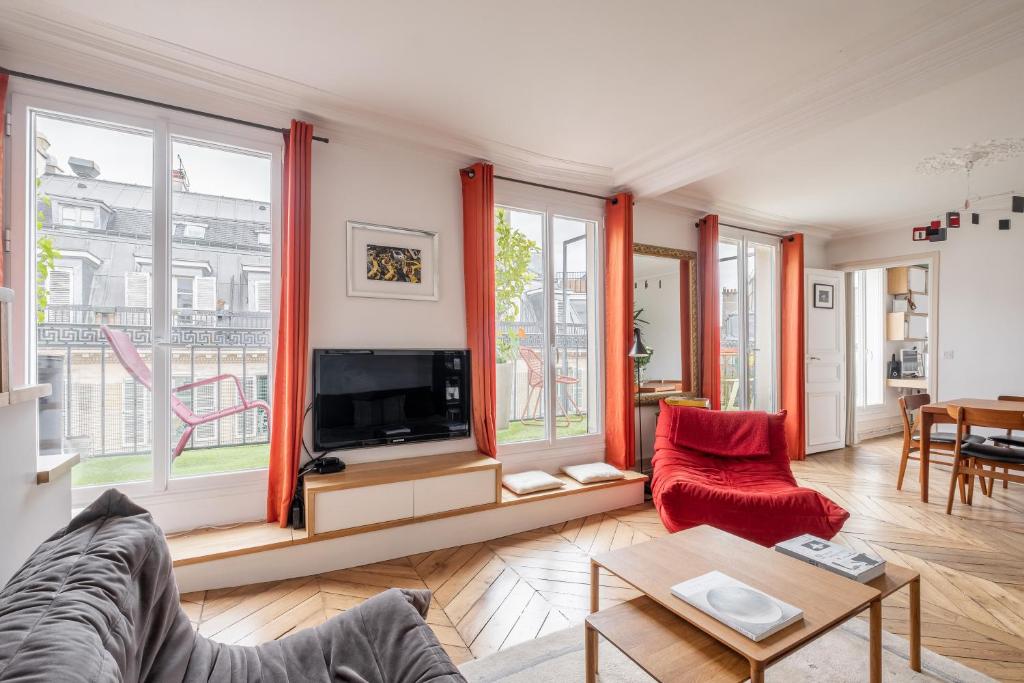 un salon avec un canapé et une télévision dans l'établissement Veeve - Spirit of Saint-Georges, à Paris