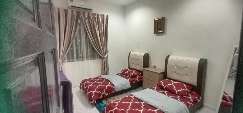 two twin beds in a room with a window at Aaira Sophea Islamic Homestay in Batu Pahat