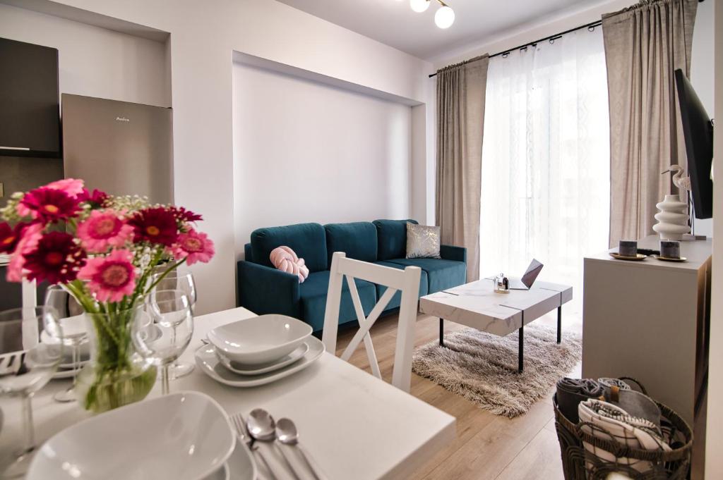 ein Wohnzimmer mit einem blauen Sofa und einem Tisch mit Blumen in der Unterkunft Apartament Lider 41 by Housine in Zator