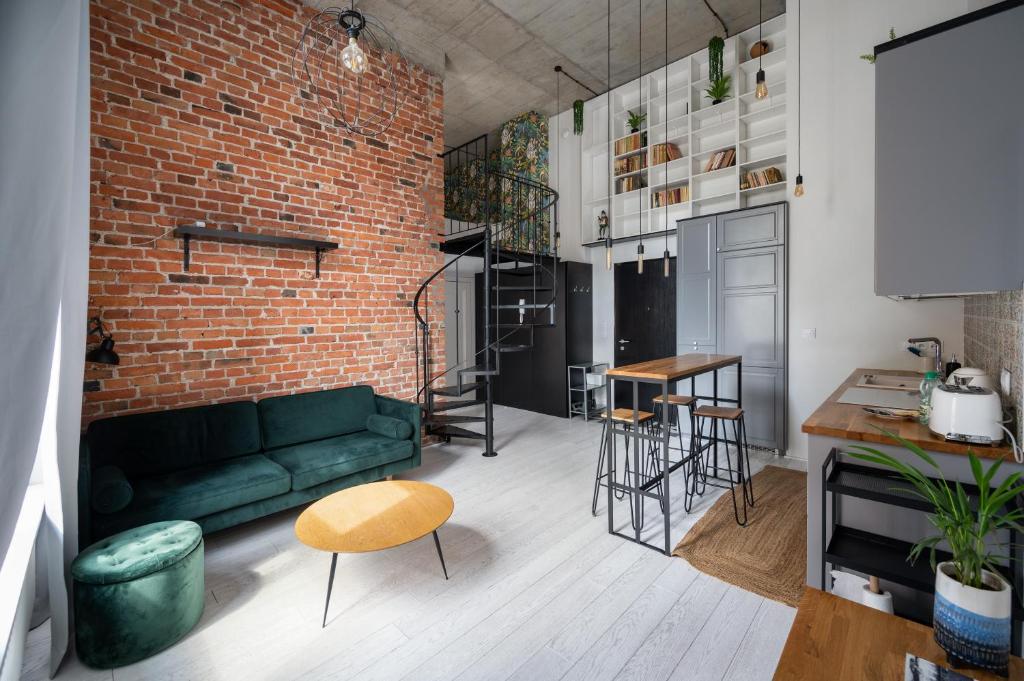 a living room with a green couch and a brick wall at Fabryka Na Pradze Loft Apartment in Warsaw