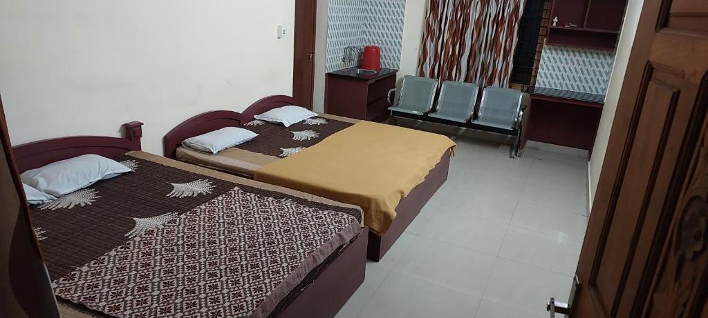 a bedroom with two beds and a window with chairs at Adithya Residency Guruvayur in Guruvāyūr