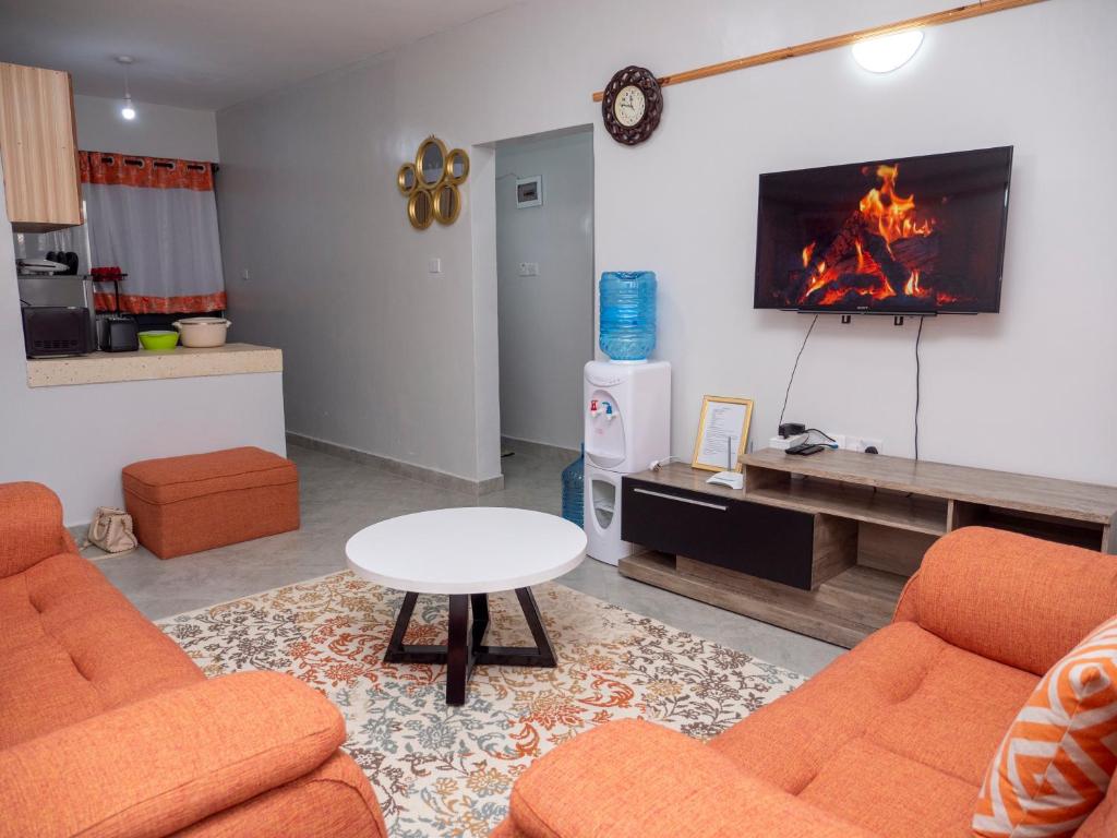 een woonkamer met 2 oranje stoelen en een open haard bij Havan Furnished Apartments- Hyrax Hill in Nakuru