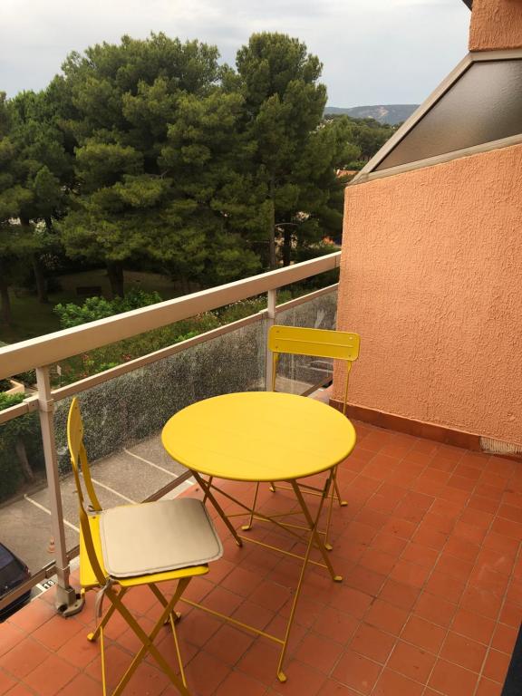 a yellow table and two chairs on a balcony at Résidence l’Amiraute in Bormes-les-Mimosas