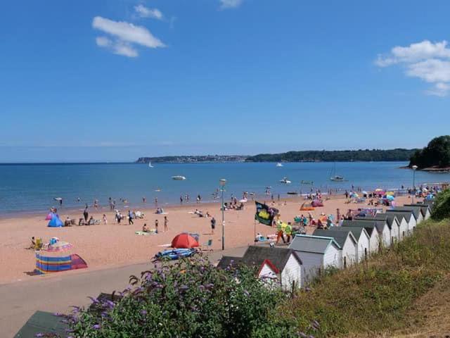 a beach with a lot of people on it at Primrose Steps in Goodrington