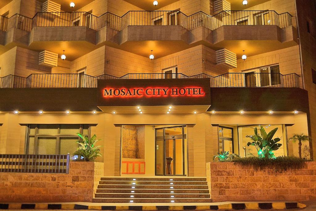 un grande edificio con un cartello che indica l'hotel riamsogenic city di Mosaic City Hotel a Madaba