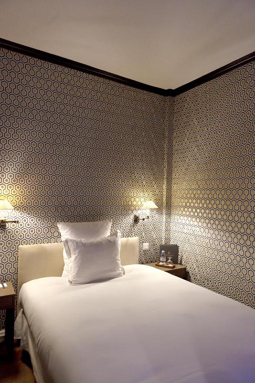 a bedroom with a white bed and a patterned wall at Hôtel du Danube Saint Germain in Paris