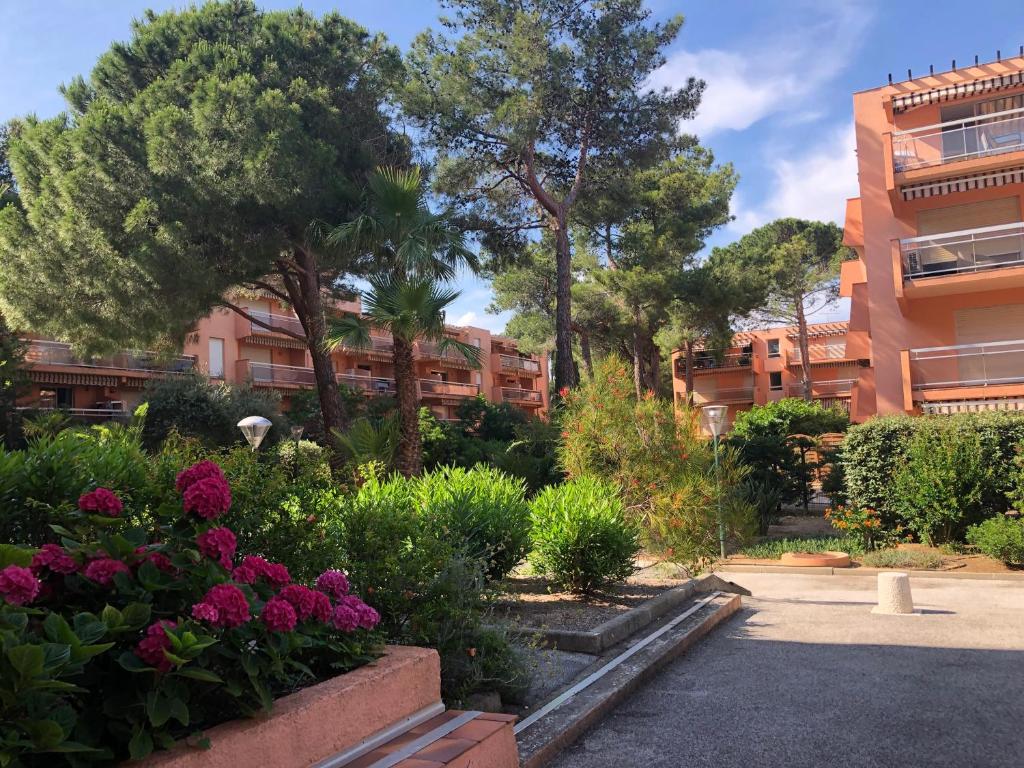 a garden in front of a building with trees and flowers at Résidence l’Amiraute in Bormes-les-Mimosas