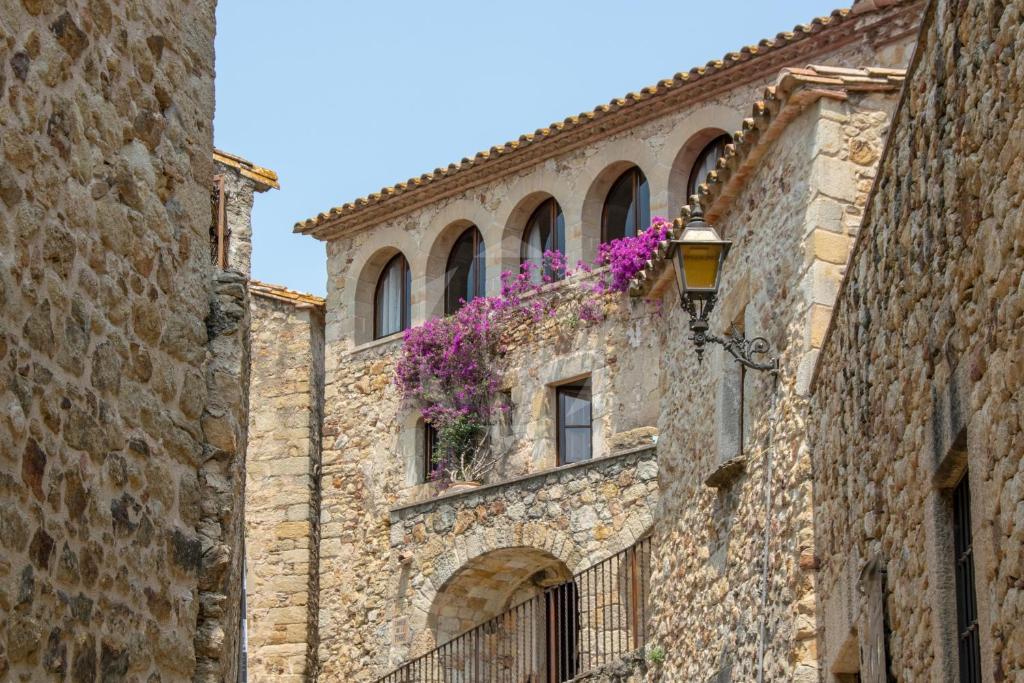 a building with purple flowers on the side of it at PALS - Maison médiévale tout confort in Pals