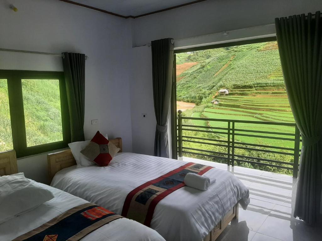 two beds in a room with a large window at Dong Suoi H'mong Homestay & Bungalow in Mù Cang Chải