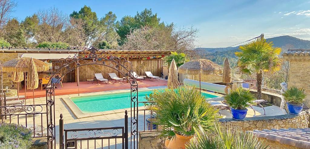 une maison avec une piscine bordée de palmiers dans l'établissement Chambres d'hôtes et Gîtes Les Restanques, à Saint-Alexandre