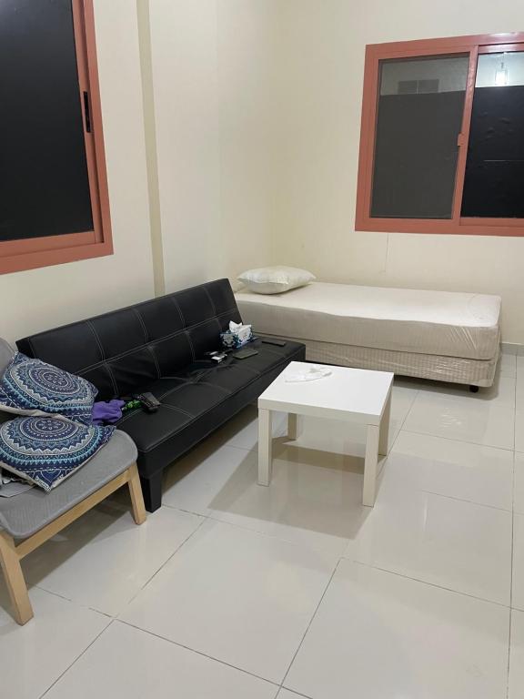 ein Wohnzimmer mit einem schwarzen Sofa und einem Tisch in der Unterkunft Najm home in Ajman 
