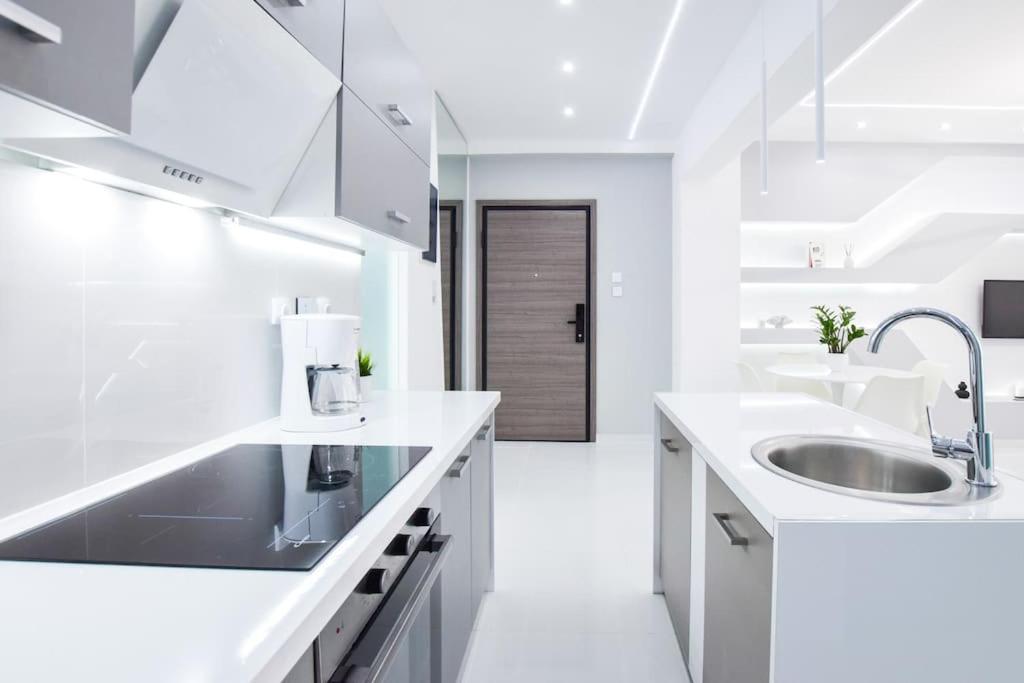 a white kitchen with white counters and a sink at Cozy two-bedroom apartment in Athens in Piraeus