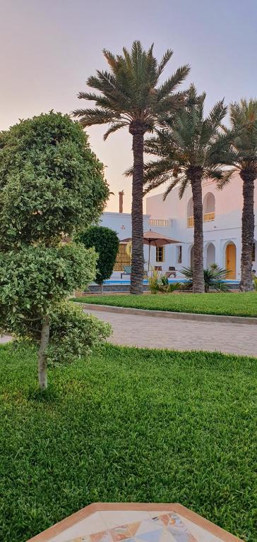 a building with palm trees in the middle of a park at Dar El Jerbi in Mezraya