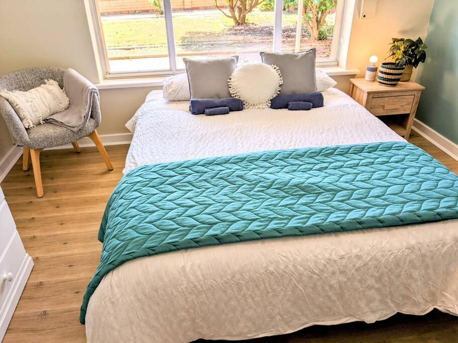 a bedroom with a bed with a green blanket on it at Holli-daze on Coast Moonta Bay in Port Moonta