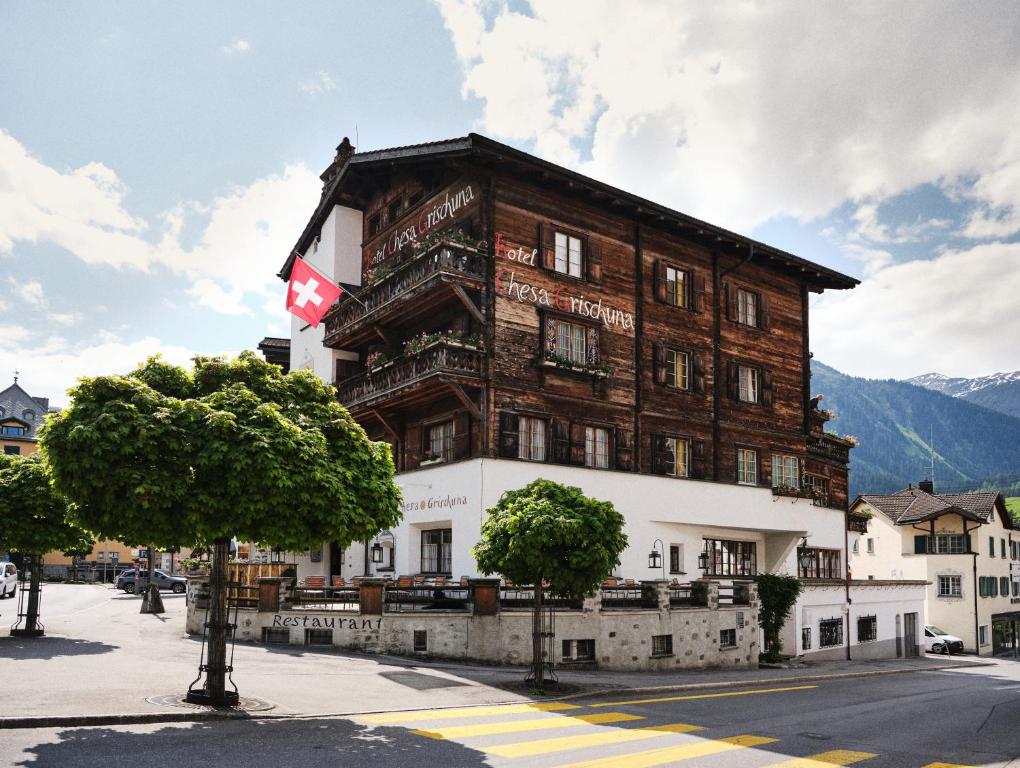 un grand bâtiment en bois arborant un drapeau canadien sur lui dans l'établissement Hotel Chesa Grischuna, à Klosters