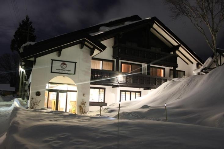 a house with a pile of snow in front of it at Snowlines Lodge Hakuba in Hakuba