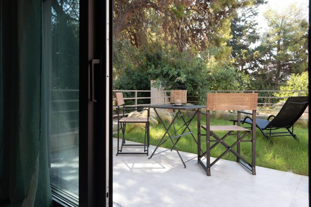 eine Terrasse mit einem Tisch und Stühlen auf einer Veranda in der Unterkunft Osiris - cozy sea walk lodge with private garden in Nea Makri