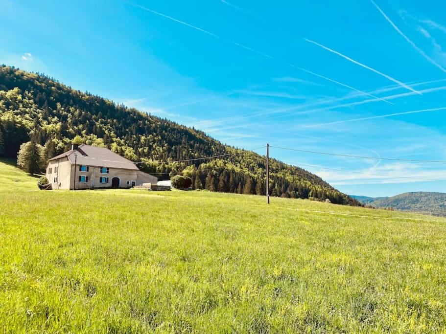 um grande campo com uma casa no meio de uma colina em Gîte 4 personnes - Pleine nature em Morbier