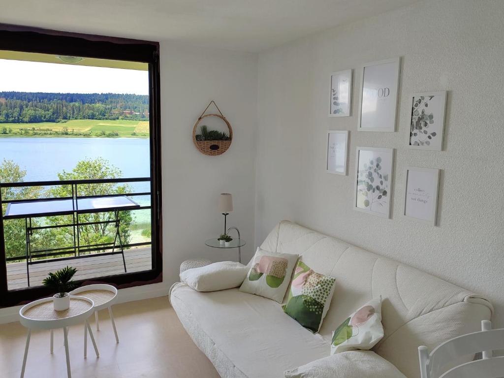 a living room with a white couch and a large window at Duplex Le Reflet du Lac in Malbuisson