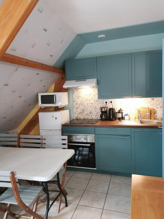 a kitchen with blue cabinets and a white table at 3 Chambres-Disneyland Paris in Saint-Thibault-des-Vignes