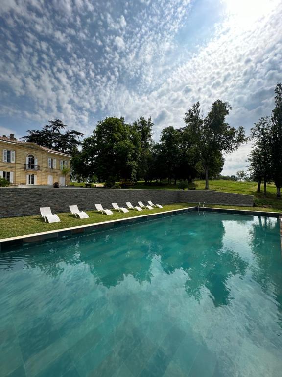a swimming pool with lounge chairs and a building at Chateau Erigoye in Beychac-et-Caillau