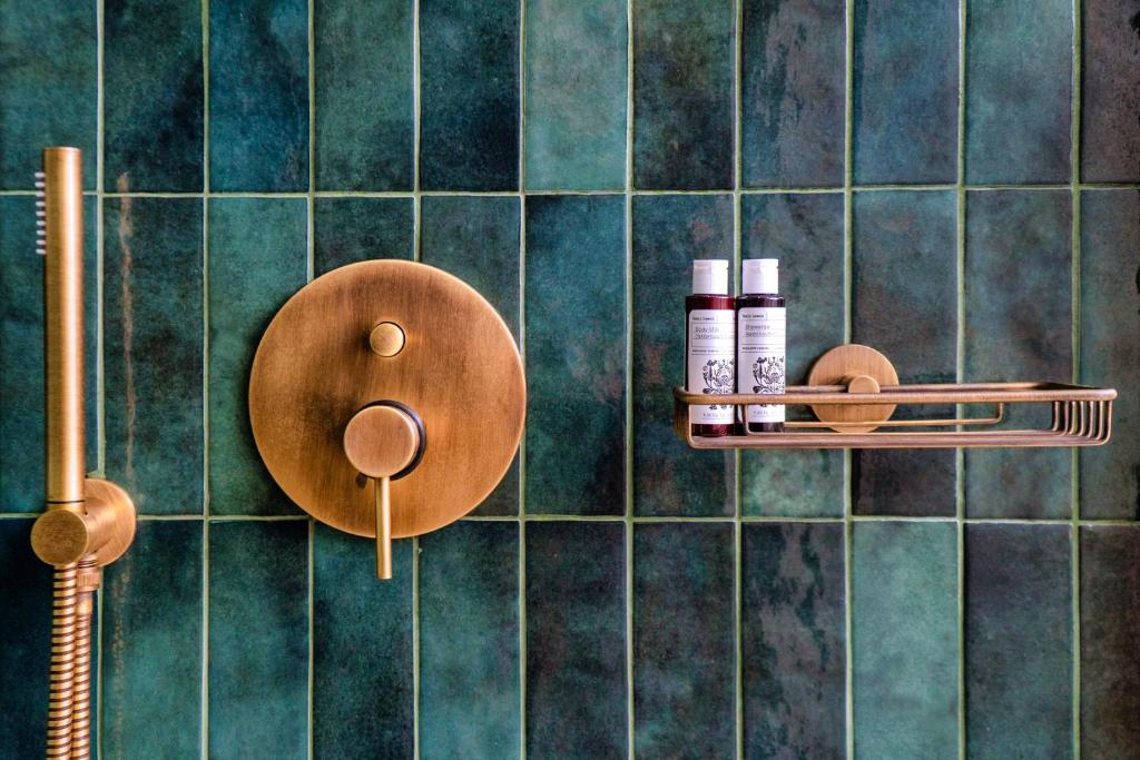 a bathroom with green tiled walls with two shelves with cosmetics at Selene in Armenistis