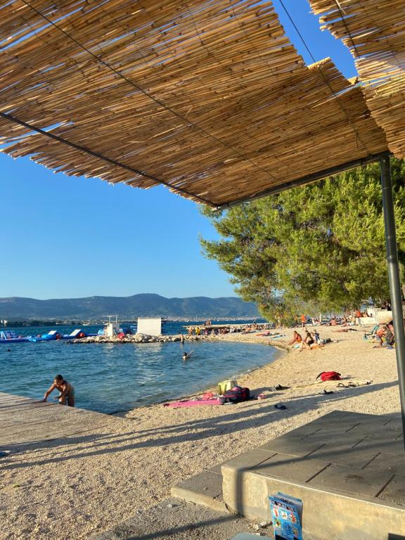 a beach with people laying on the sand and water at Family House Ljubica in Trogir