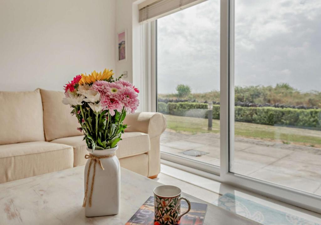 a vase of flowers on a table in a living room at Bayview Apartment - Machynys in Llanelli