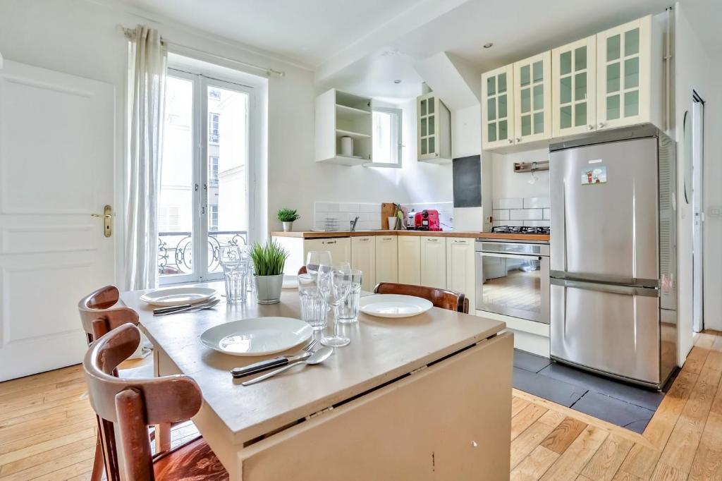 une cuisine avec une table et un réfrigérateur dans l'établissement Appartement Quartier Pigalle Free Netflix, à Paris