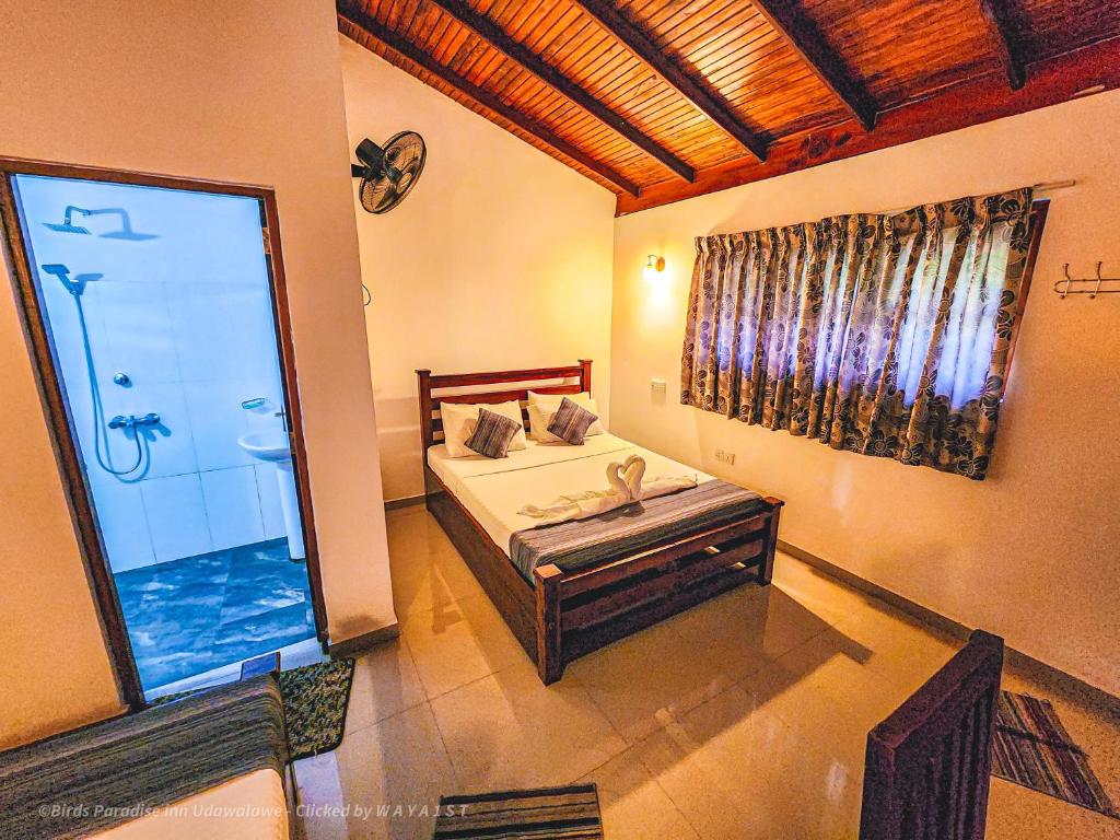 a bedroom with a bed and a large window at Birds Paradise Inn in Udawalawe